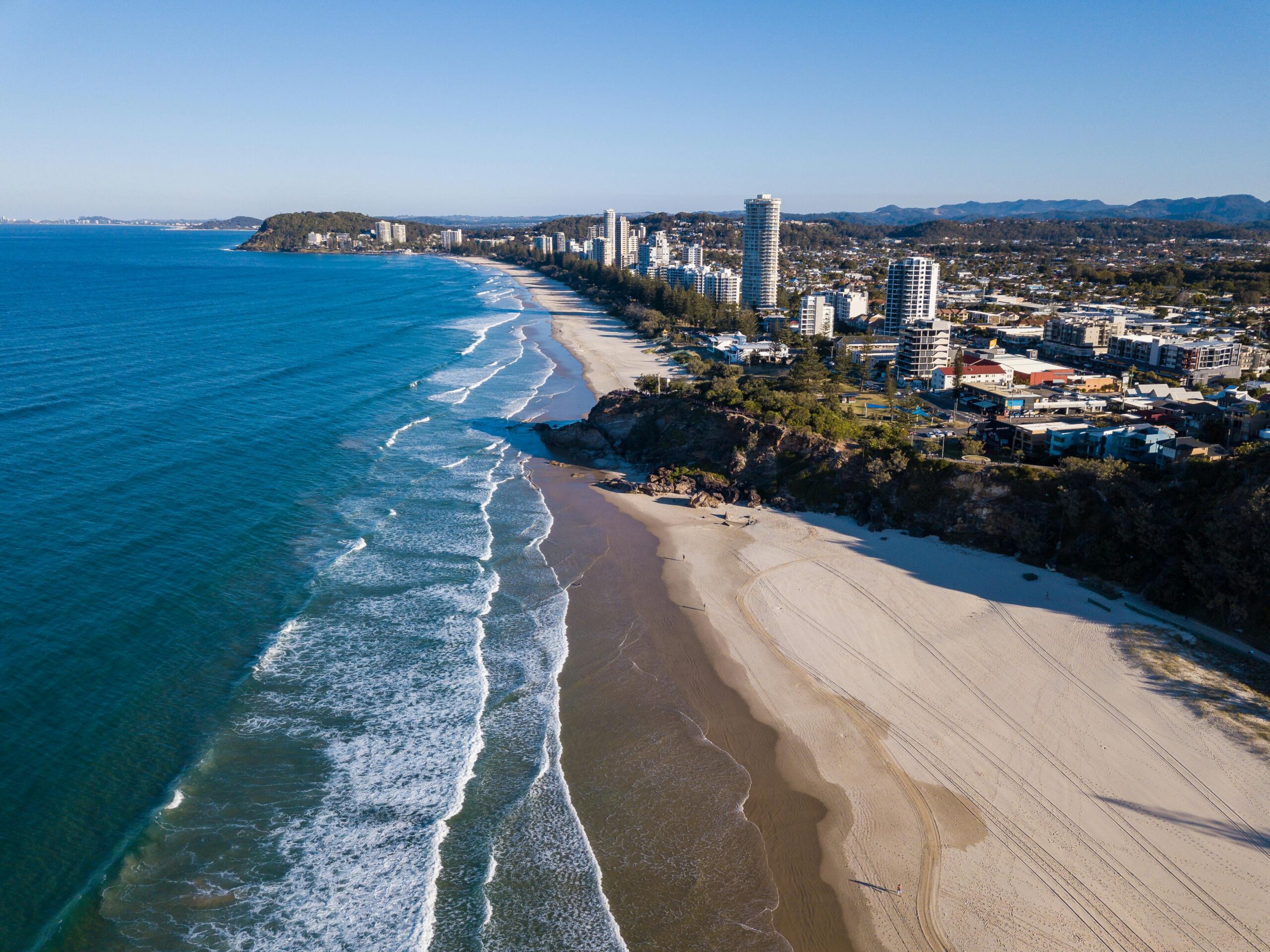 Stunning aerial view of coastline with beaches, city skyline, and scenic ocean.