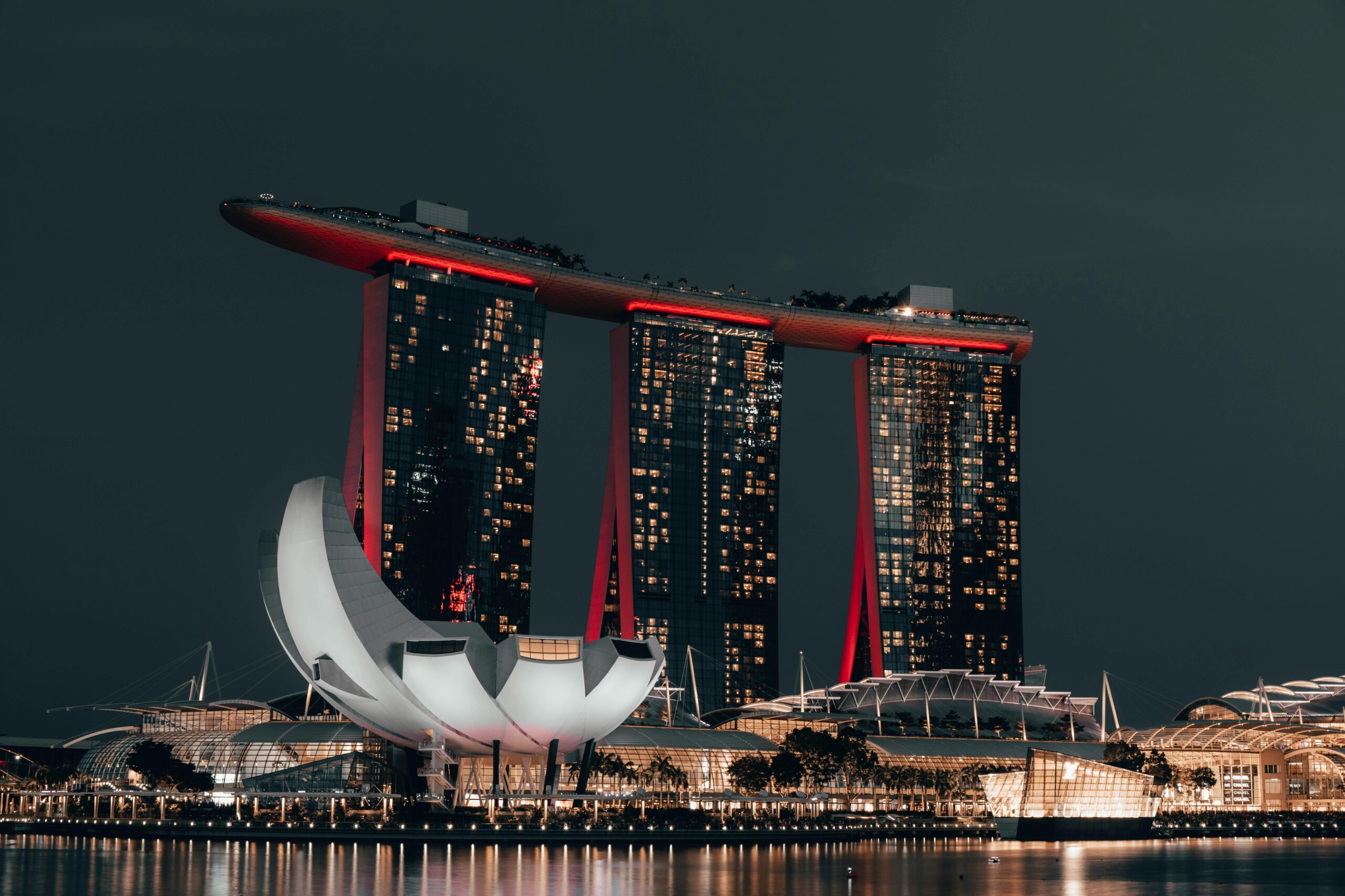 Dramatic night view of Marina Bay Sands, Singapore, with glowing cityscape and reflection.